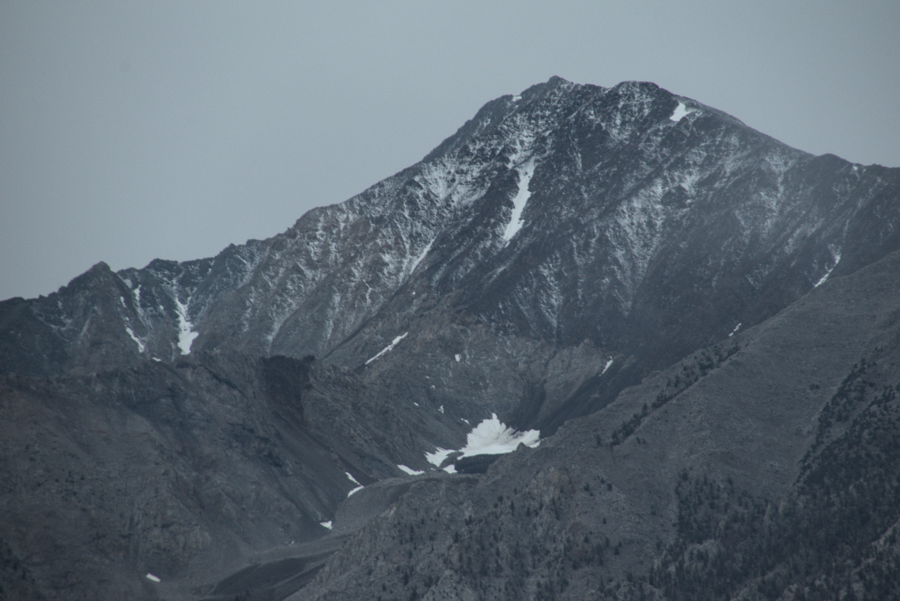 Mt Tom, tall, craggy, with a triangular peak, dark under cloudy skies, has a few large snow fields left at the beginning of fall, but those clouds also brought a light dusting of fresh snow.