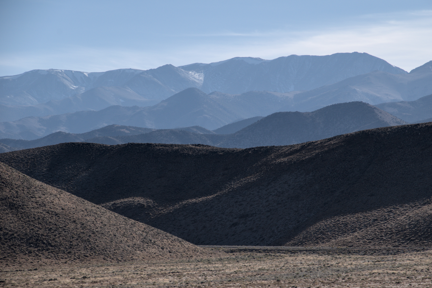 The view changes from desert floor to high mountains, with layers of foothills in between.  The further you look, the paler each range is, as light is scattered by haze.