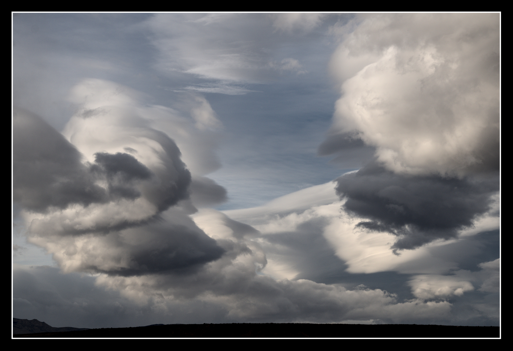 A large, varied cloud formation fills the sky, but with gaps so blue can be seen behind. There are smooth sections, rough parts, towers, some are white, some grey.