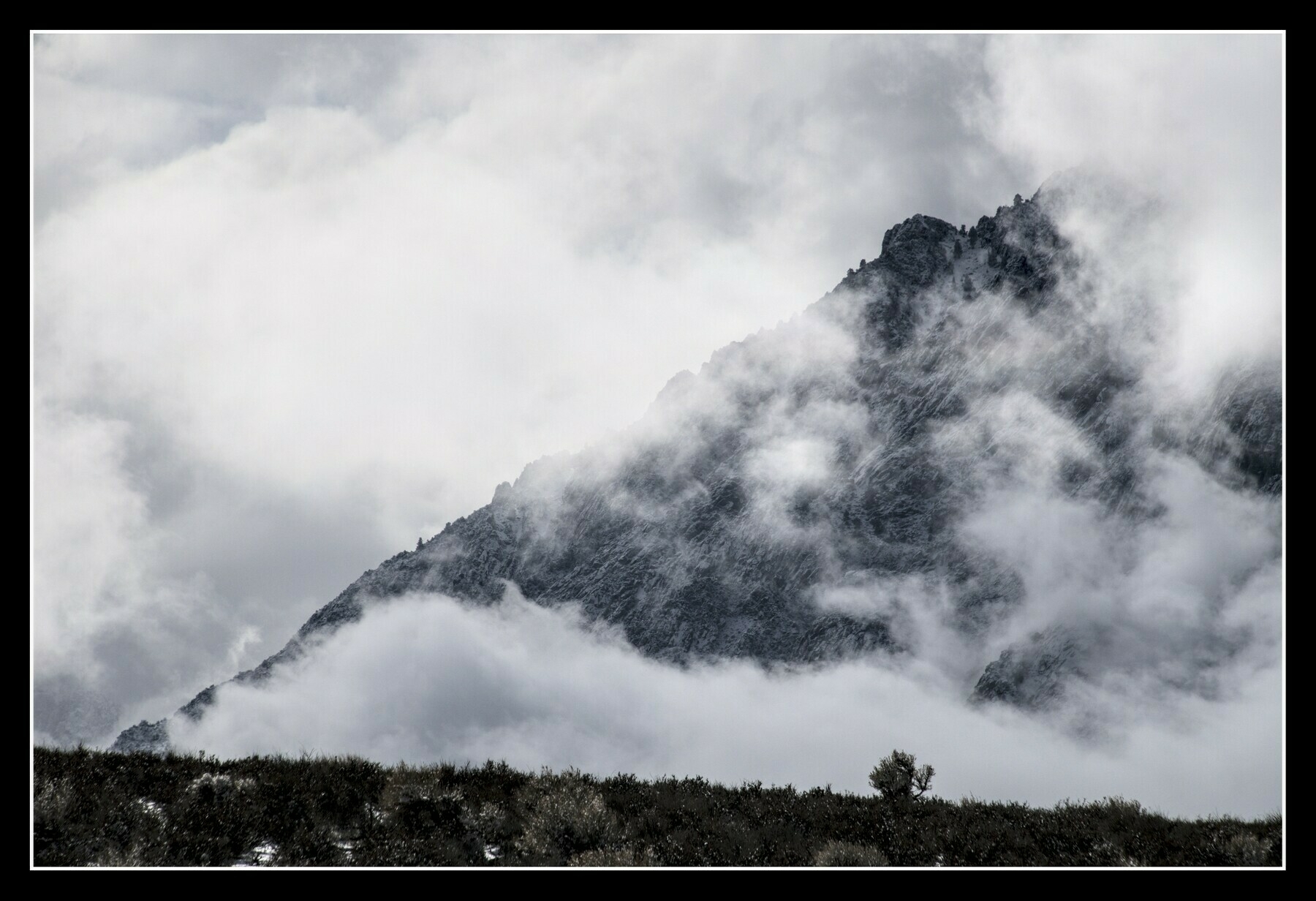 A dark, sloping mountain ridge is partially obscured by clouds.