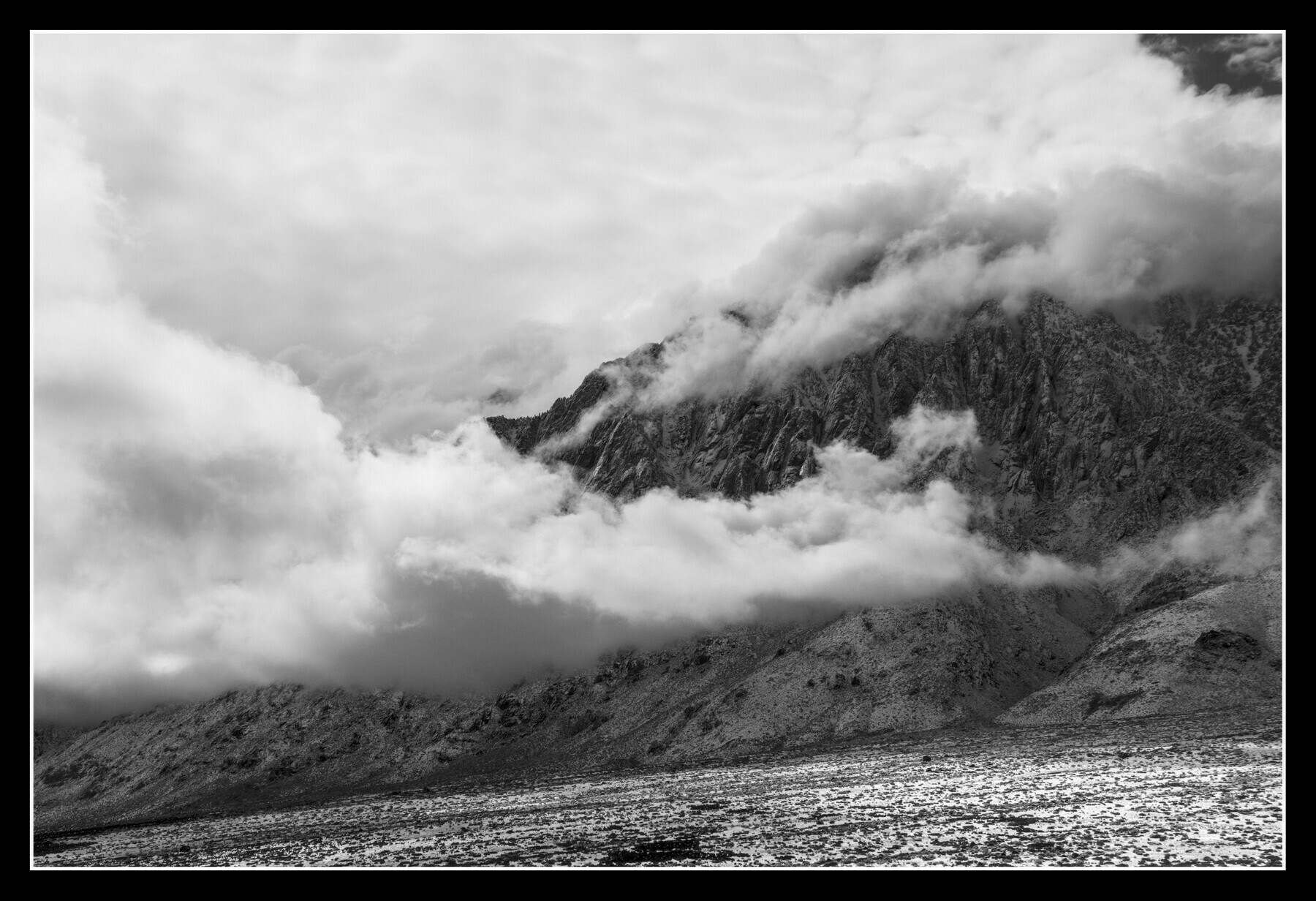 Clouds are scattered along a mountain ridge at various altitudes.