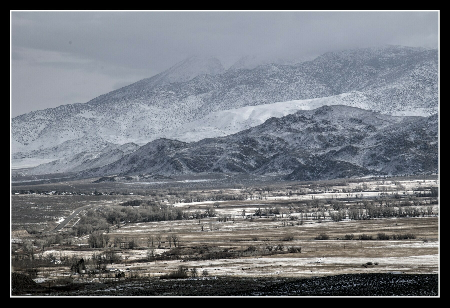 A valley floor is lightly covered with snow.