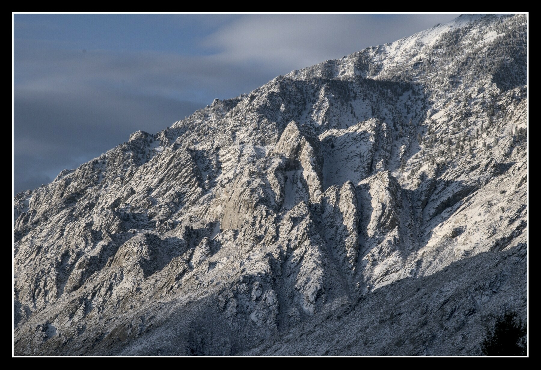 Jagged mountain spires are covered in a dusting of snow, let by early morning light.