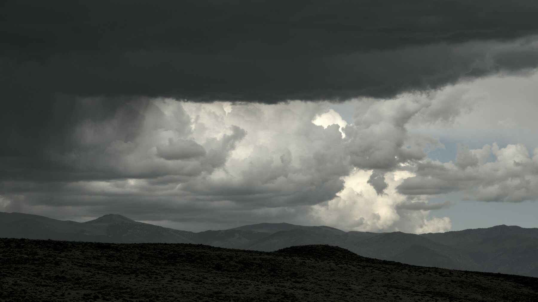 Mountains, light clouds, and dark clouds form three distinct layers.