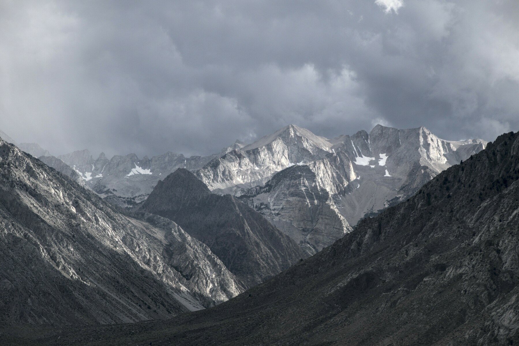 A v-shaped valley between mountains shows snow-covered, jagged peaks in the distance.