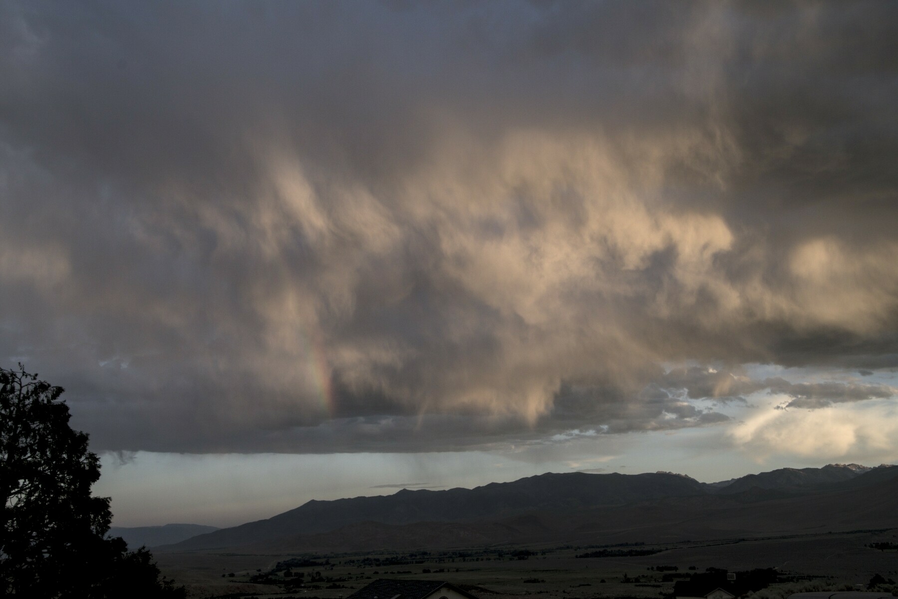 A bank of clouds over a mountain is lit by low sunlight.