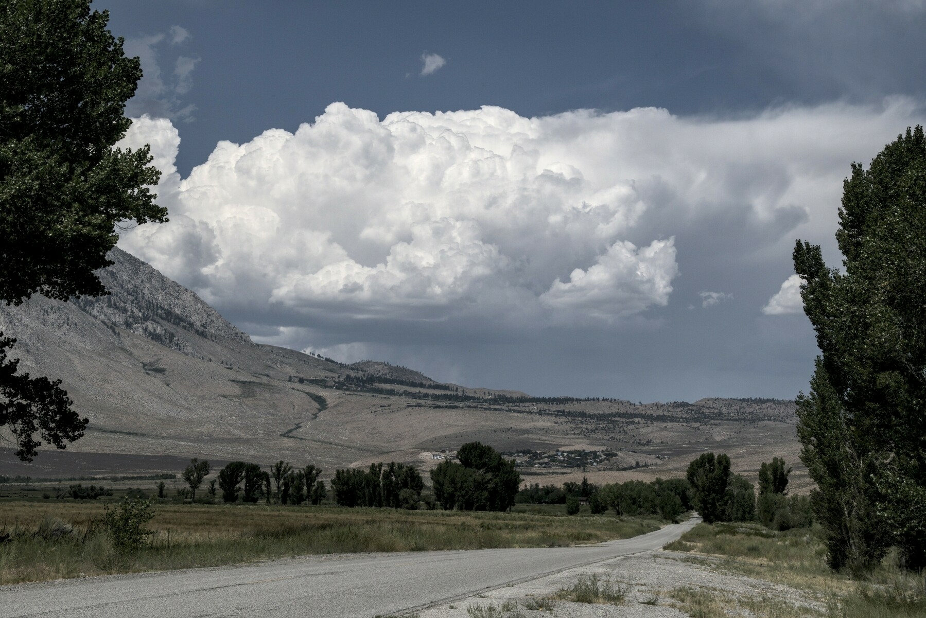 A bank of cottony clouds appears around the shoulder of a a mountain.