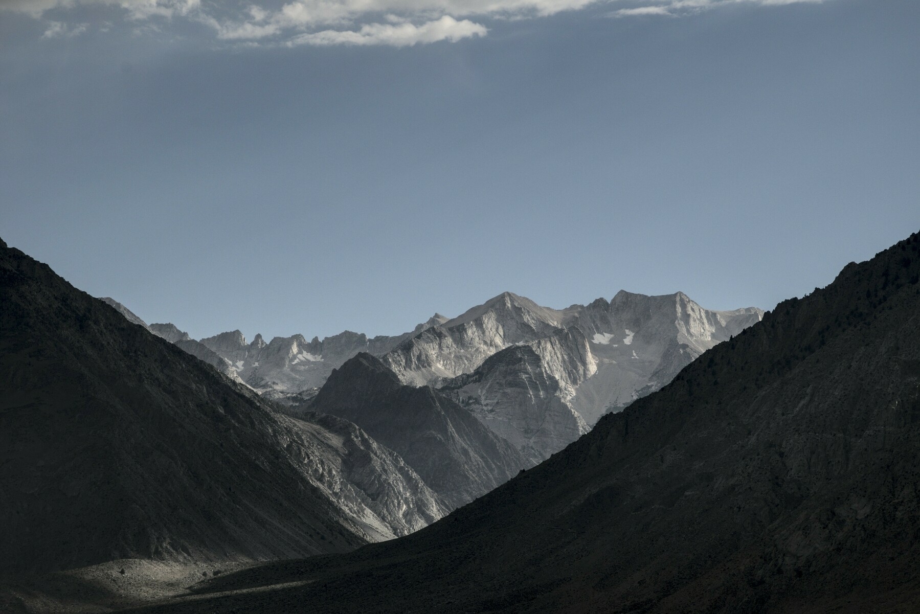 A deep vee between mountains reveals glacially carved peaks in the distance.