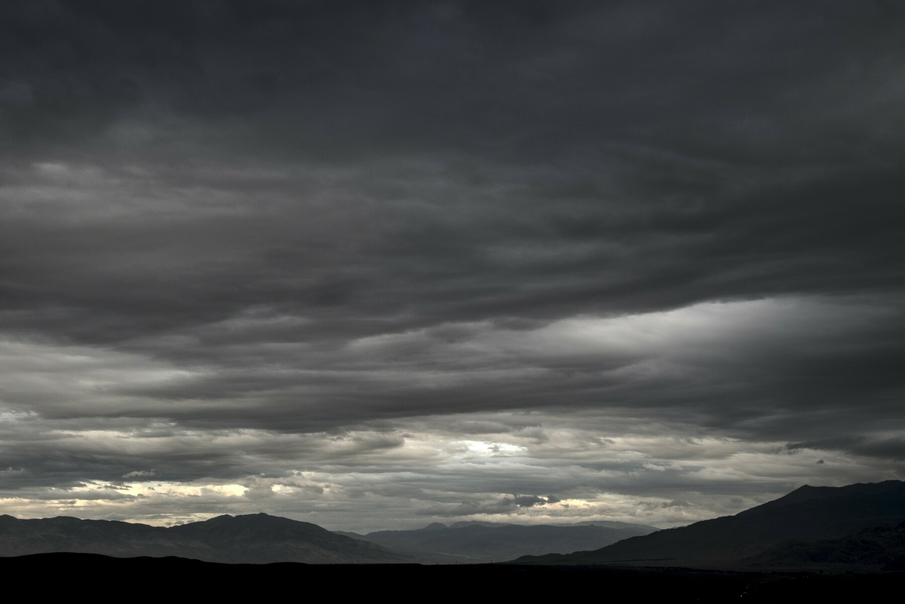 A cloud layer covering the whole sky varies in form and lightness.