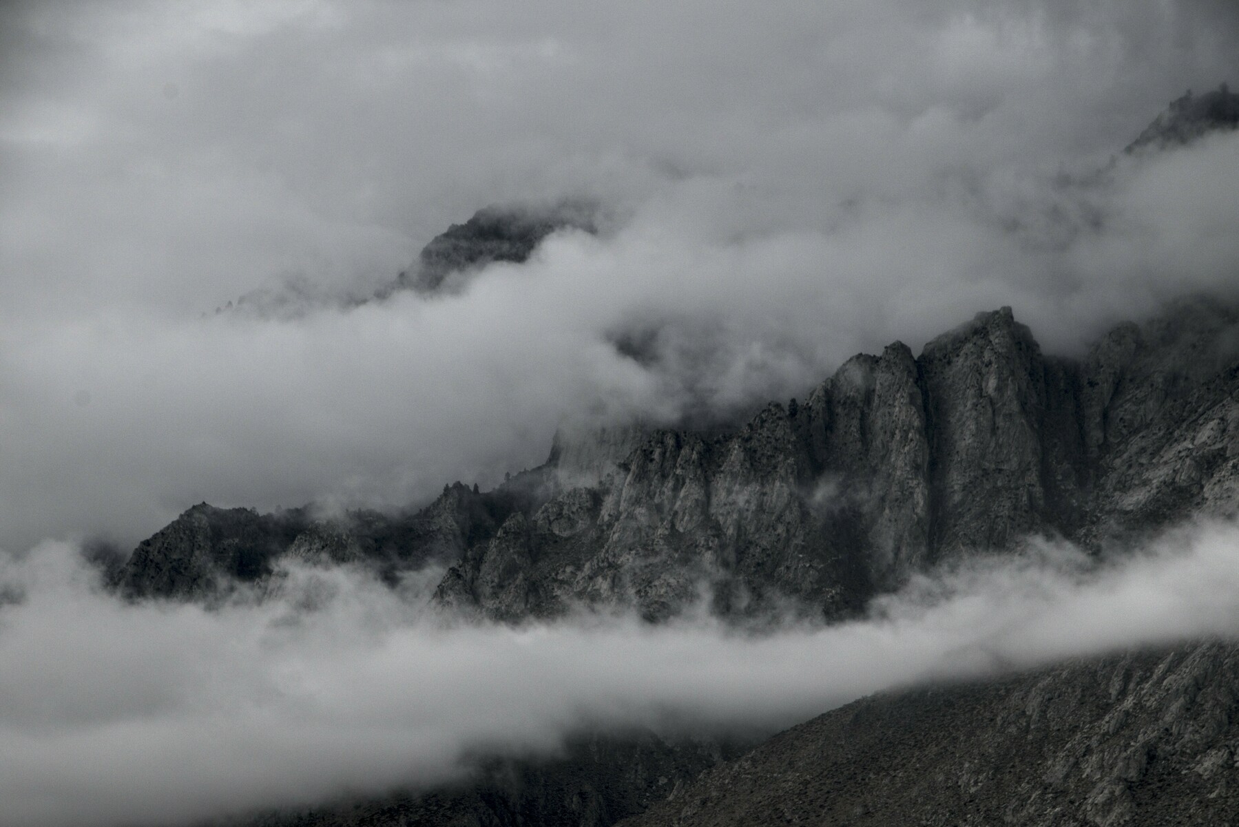Clouds settle on a mountain wall.