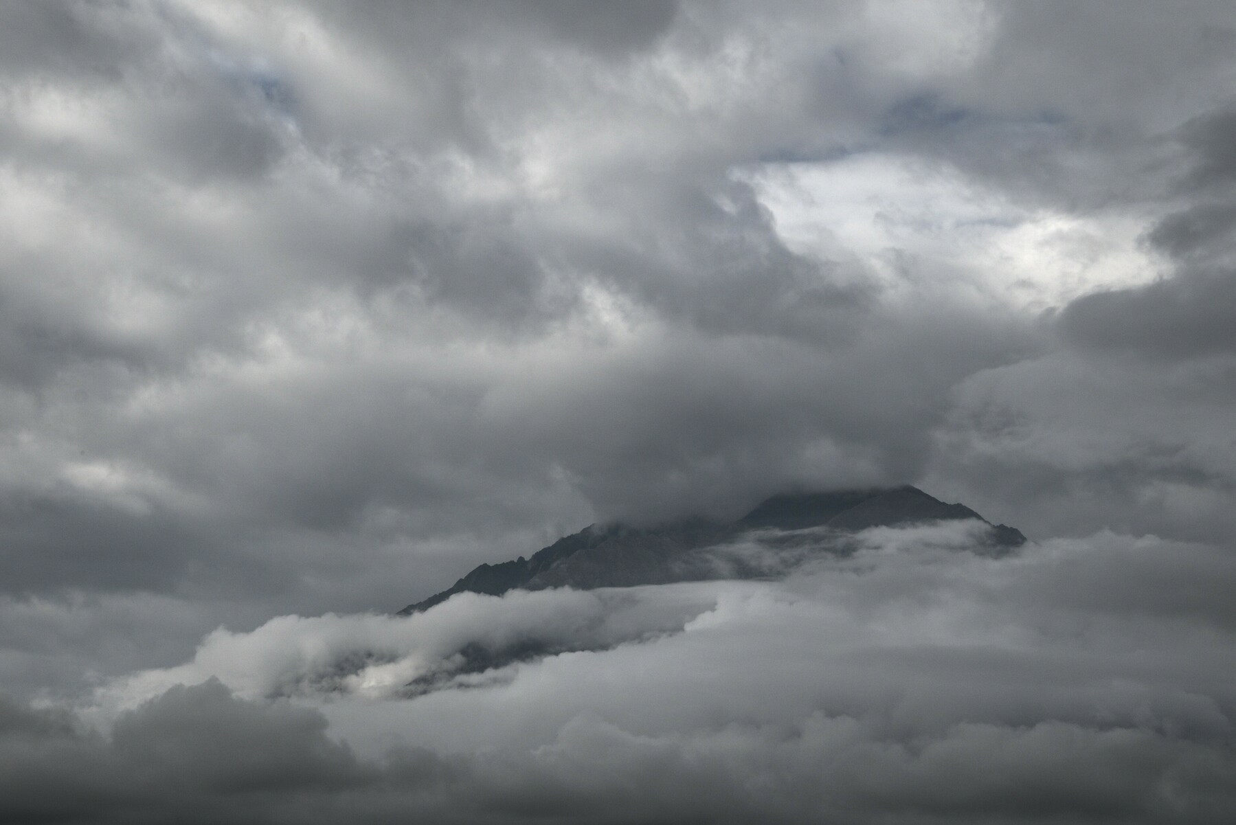 A large triangular mountain is obscured by clouds.
