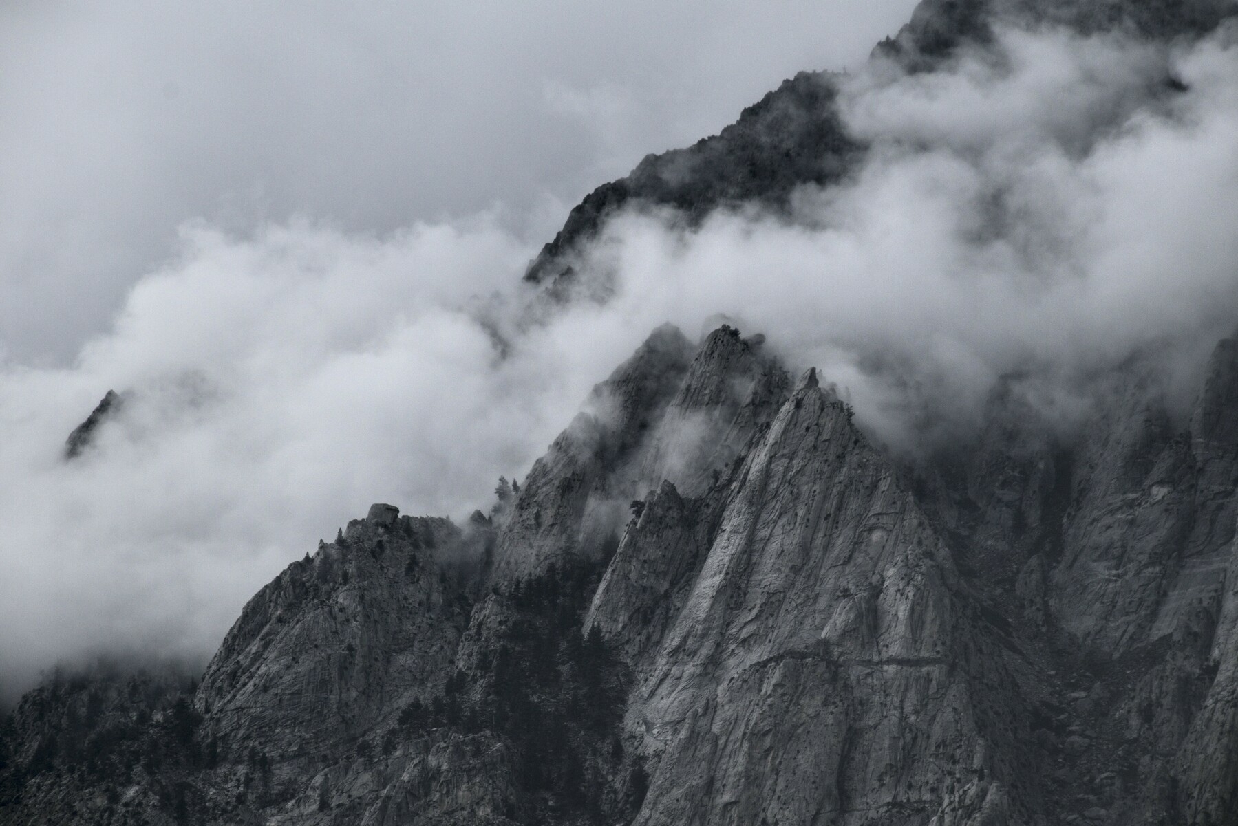 Clouds lie in the depressions of a rocky mountain face.