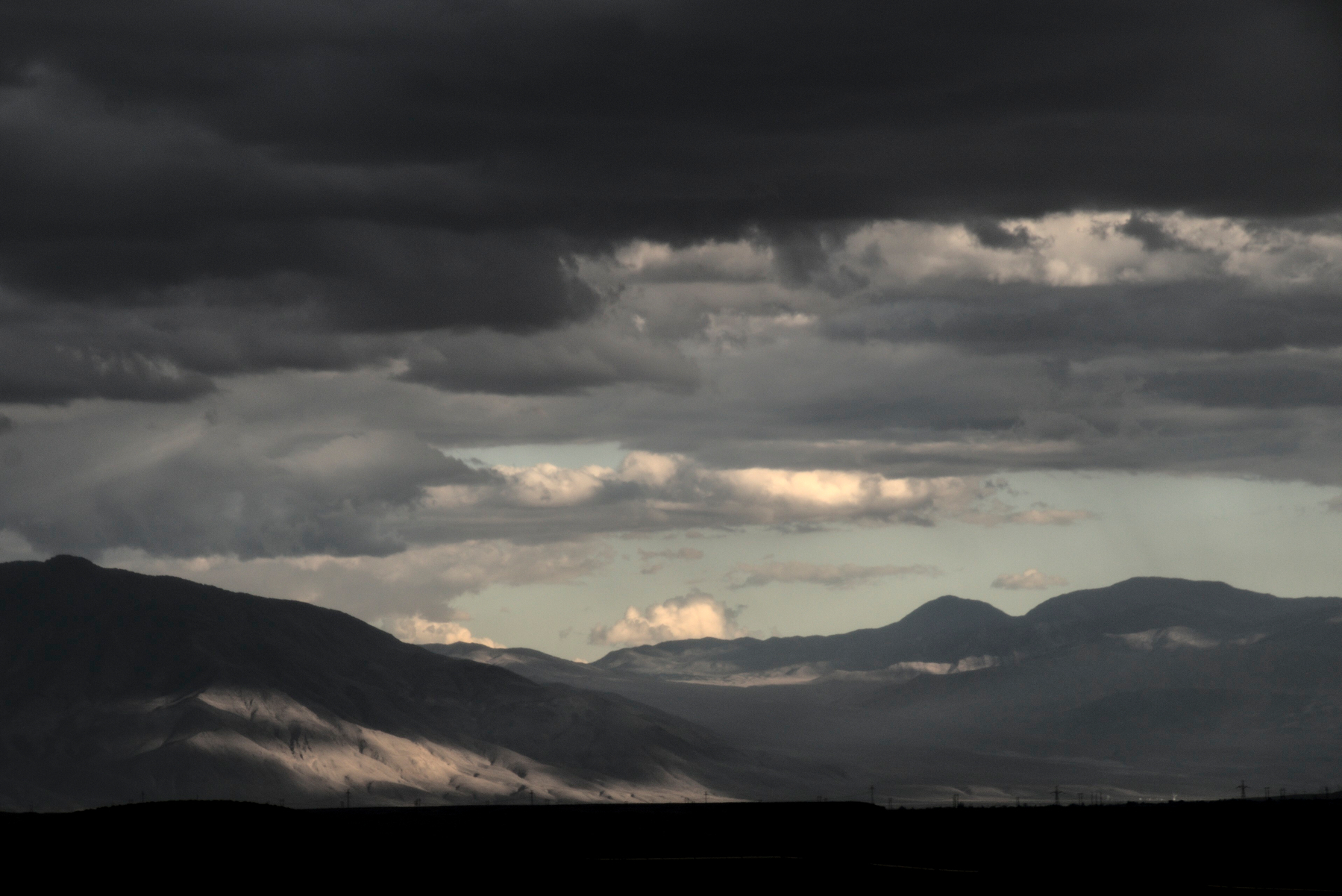 A storm over mountains on the left gives way to blue skies on the right.