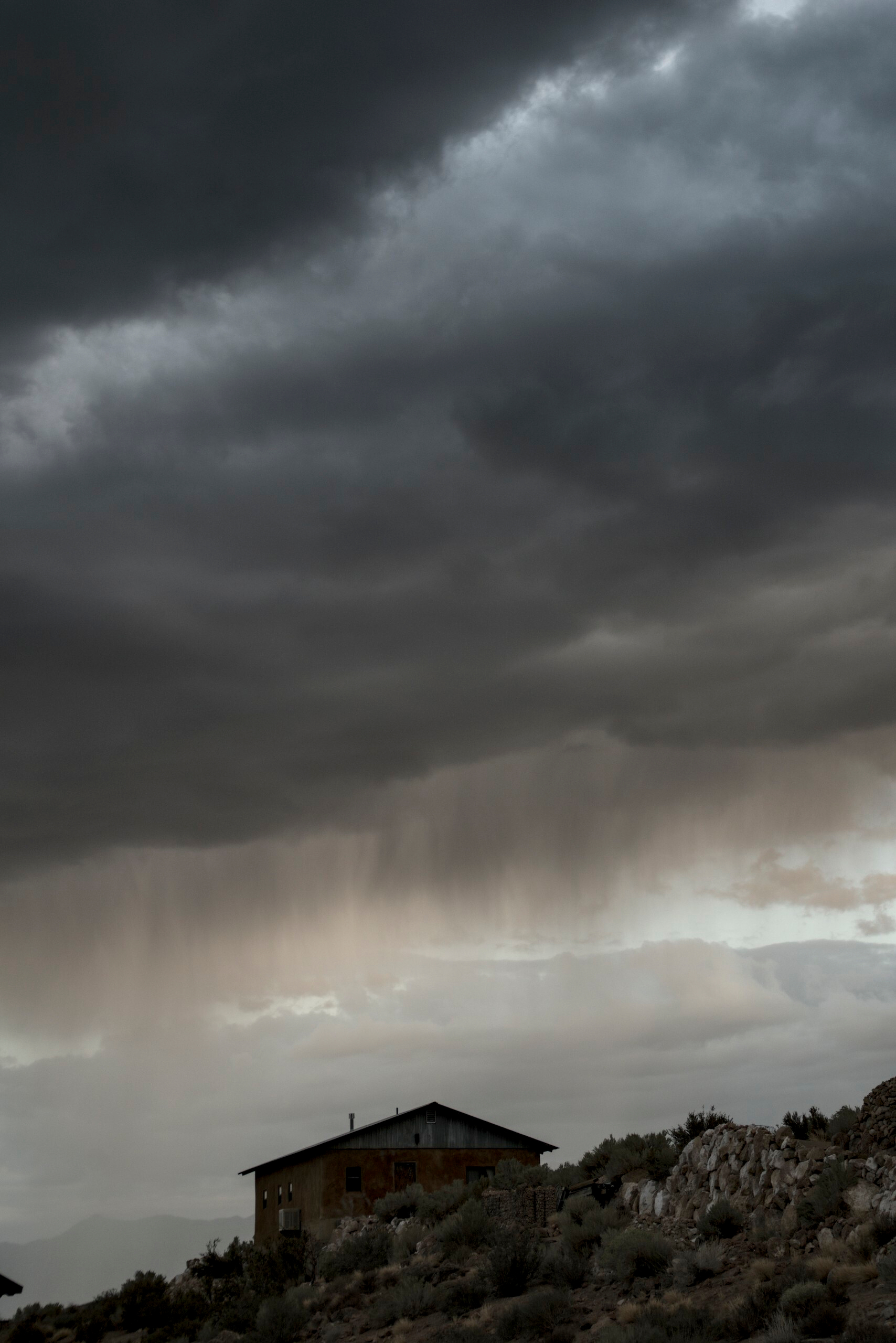A house in the foreground offset a layered dark sky.