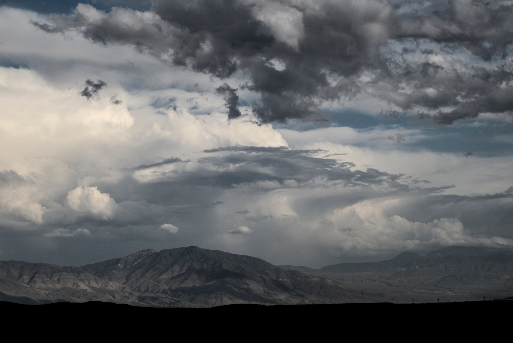 Varied clouds loom over a long mountain range.