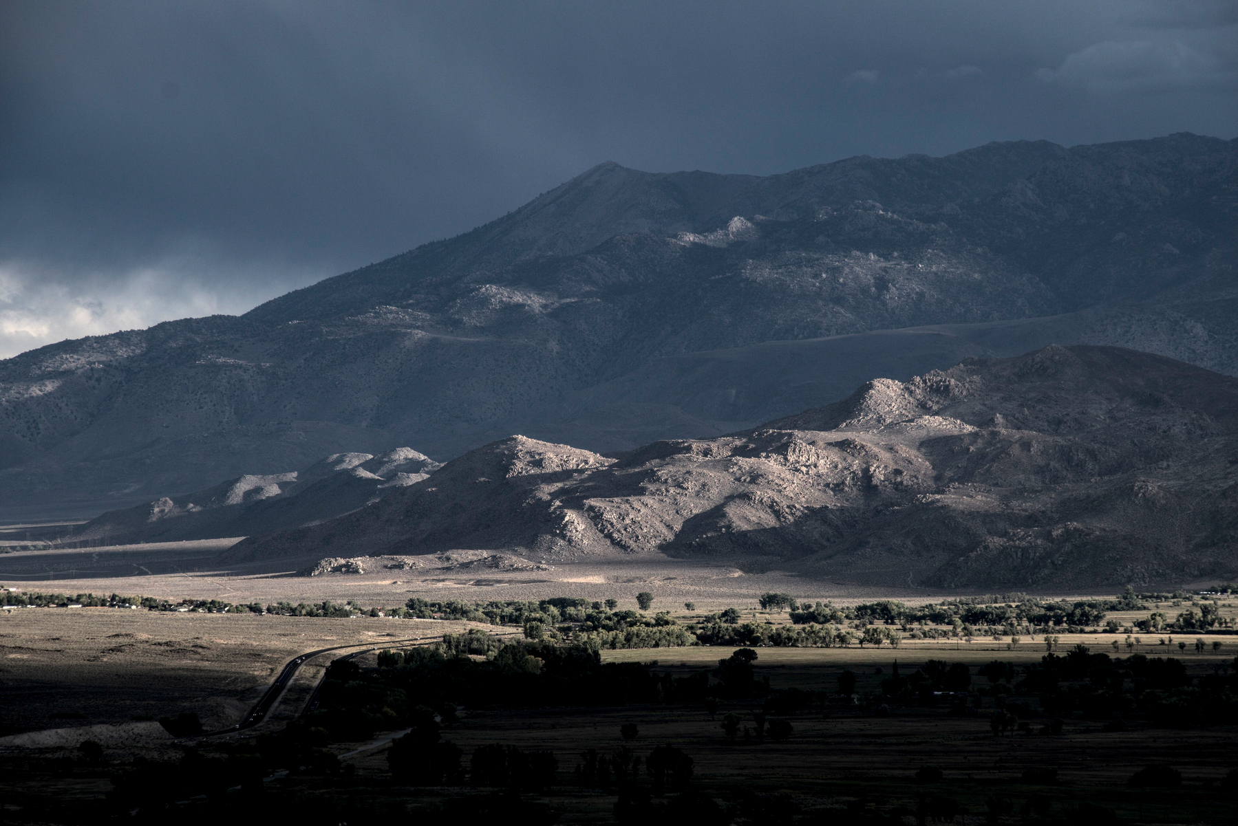 Rough, stony foothills are lit by low, slanting light.
