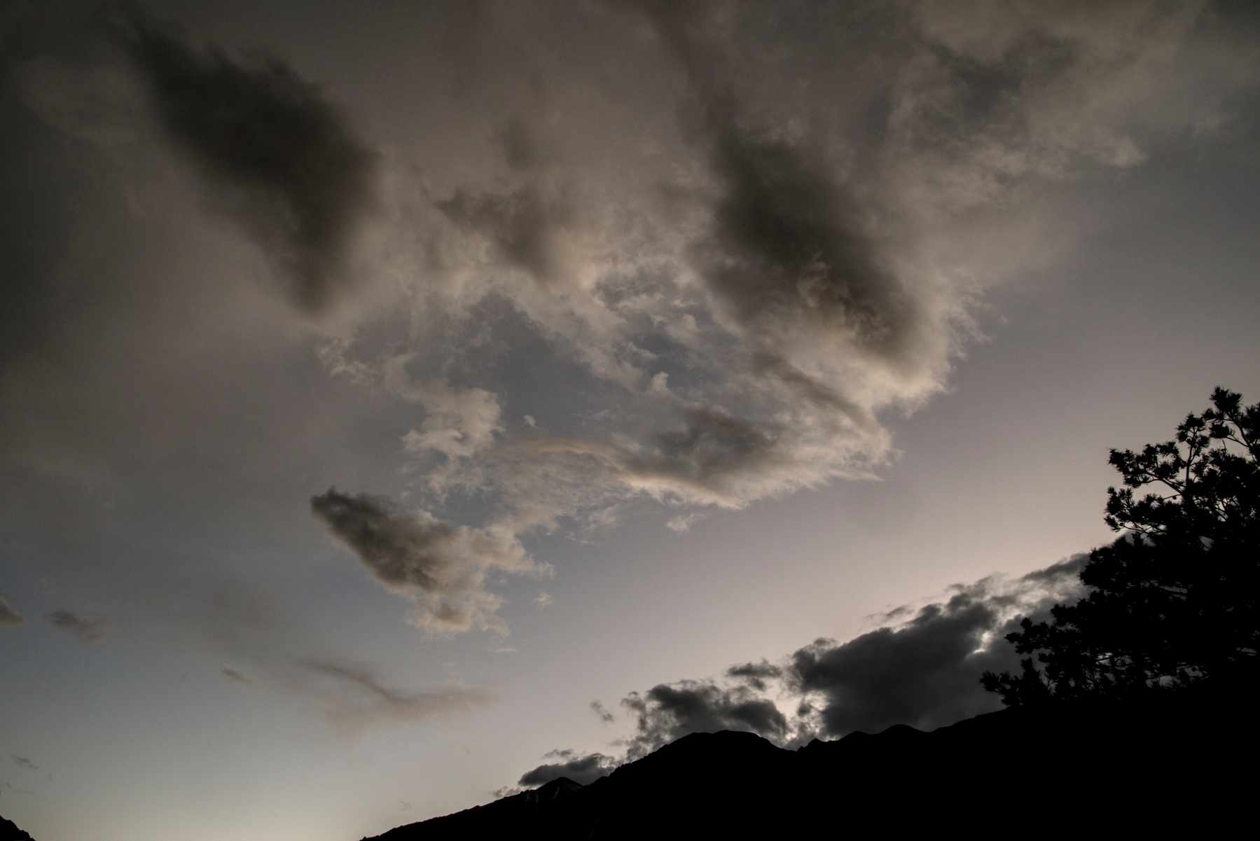 Soft grey fragmented clouds over mountain ridge.