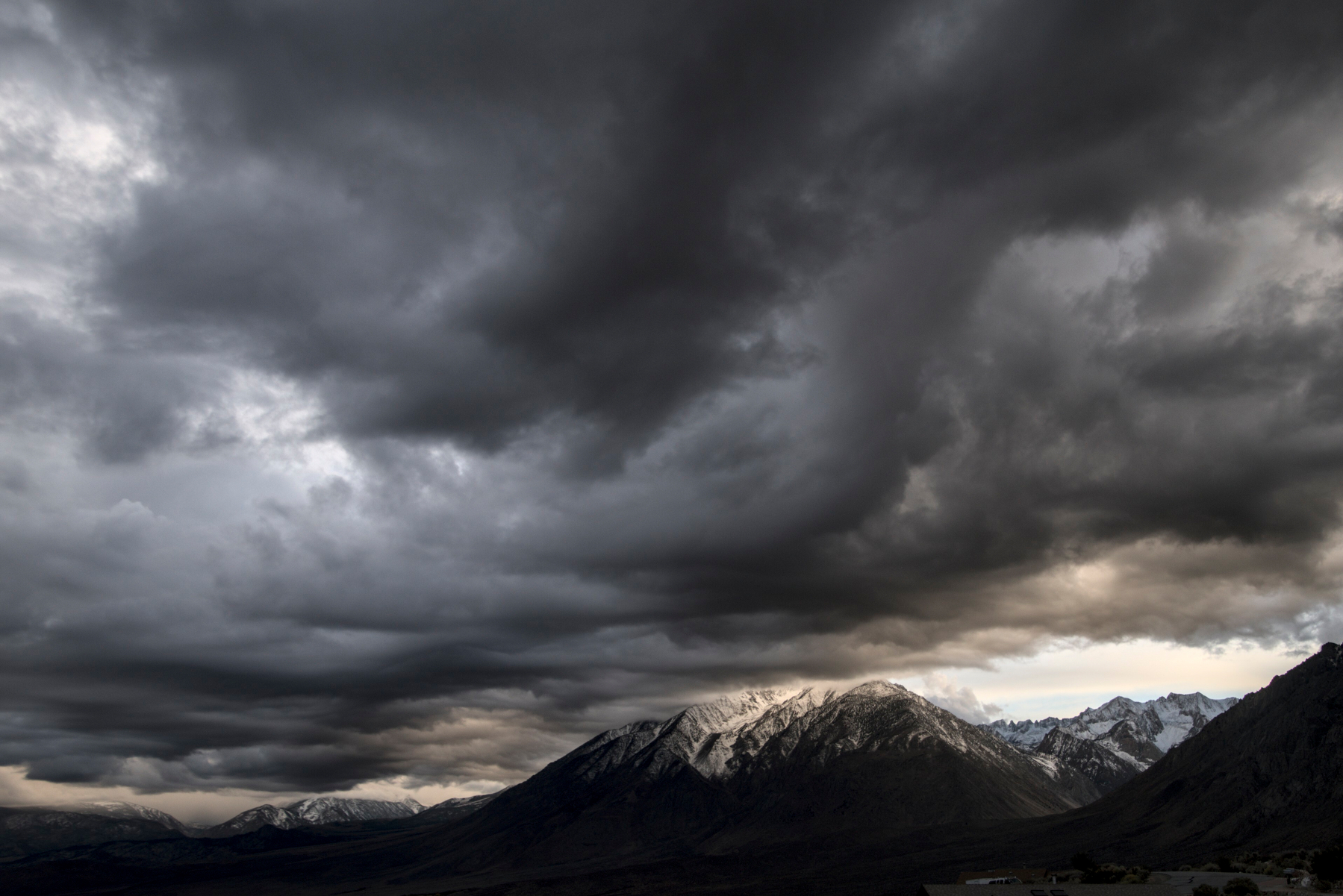 Dark clouds form a flat layer above a mountain valley.
