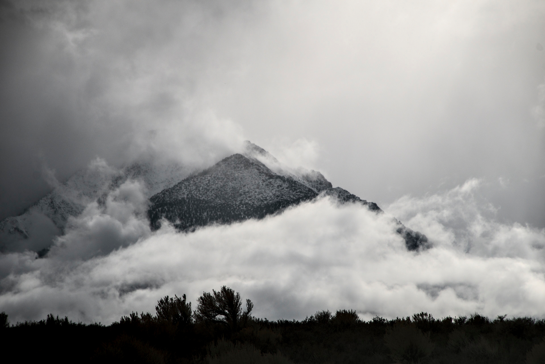 A triangular face juts out from a mountain covered in fog.