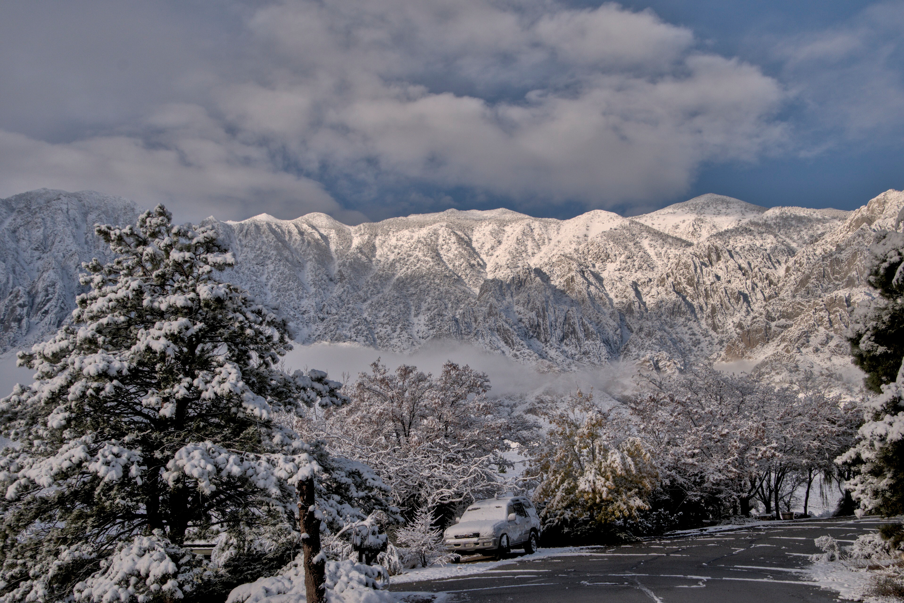 A snow covered street fills the foreground while a high mountain face rises behind.
