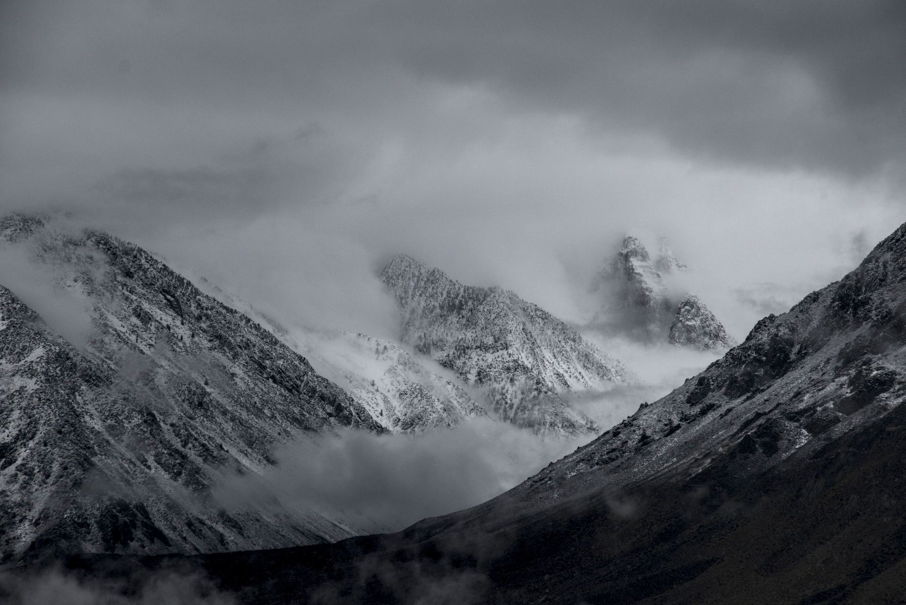 Jagged mountains with fresh snow, wreathed in clouds.