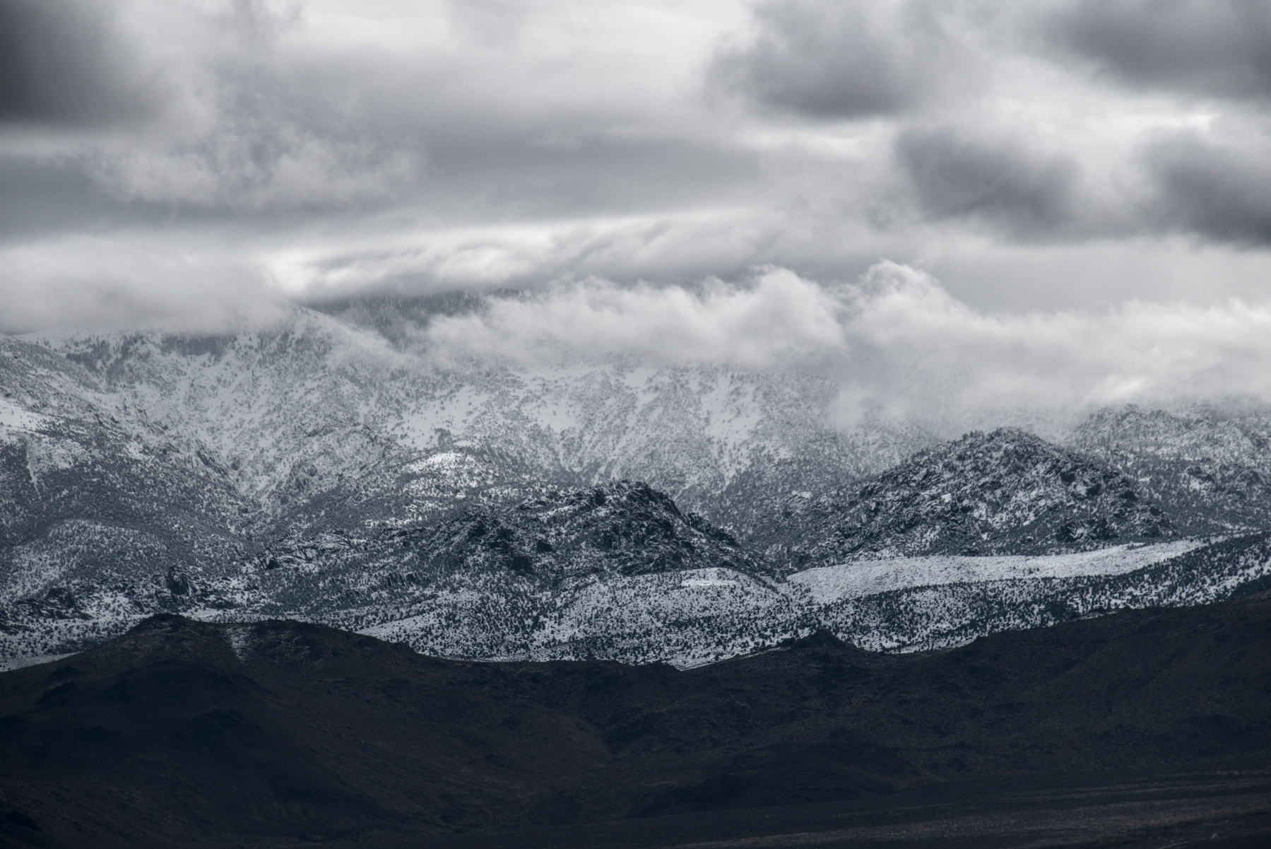 A mountain scene with clouds and partial snow coverage.