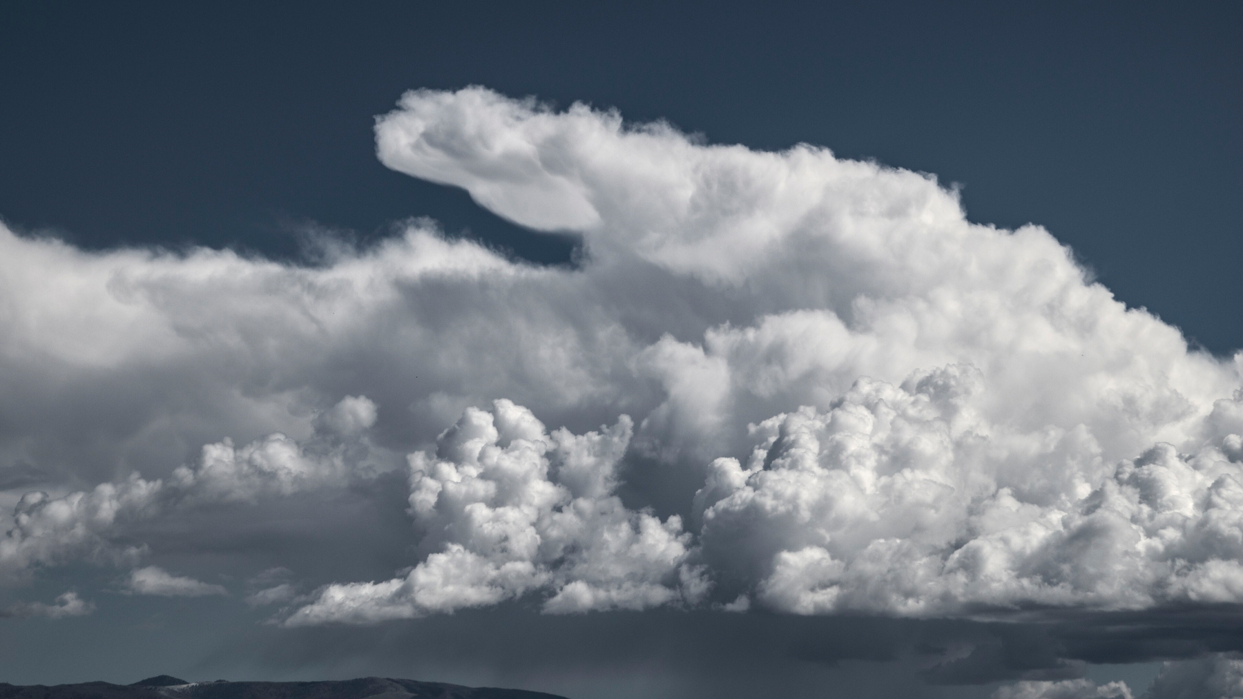 A group of cumulonimbus clouds with an oddly shaped projection out the top.