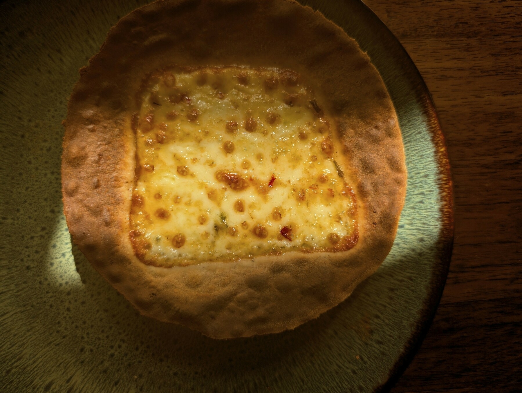 Grilled cheese on a tortilla lit in a film noir style.