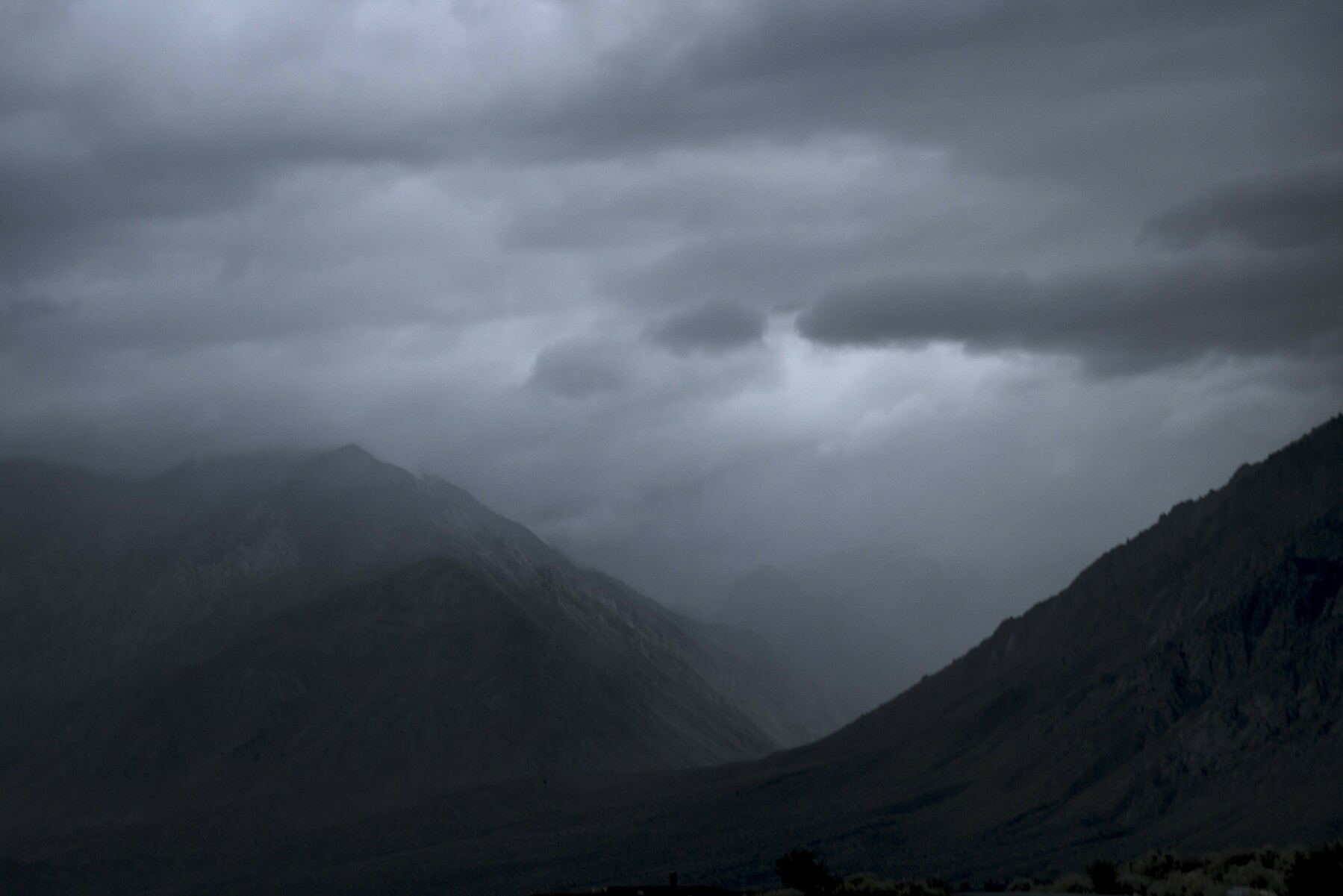 A deep mountain canyon is covered by a dark storm.